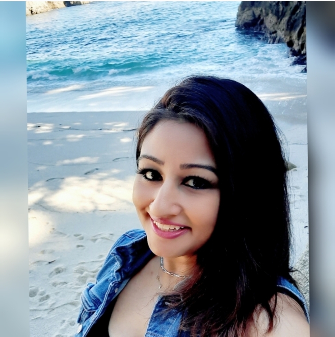 Smiling woman, instructor Shaleen, stands in front of blue water. 